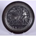 AN EASTERN WHITE METAL DISH, decorated in relief with a male herding cows. 22 cm wide.