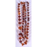 AN EARLY 20TH CENTURY LONG STRAND AMBER BEAD NECKLACE, formed with flattened facetted beads. 108 cm