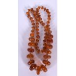 A 1920'S ART DECO AMBER NECKLACE, formed with flattened circular beads. 63 cm long and weight 52 gr