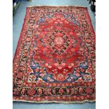 AN ANTIQUE PERSIAN RED GROUND RUG, decorated with extensive foliage. 207 cm x 125 cm.