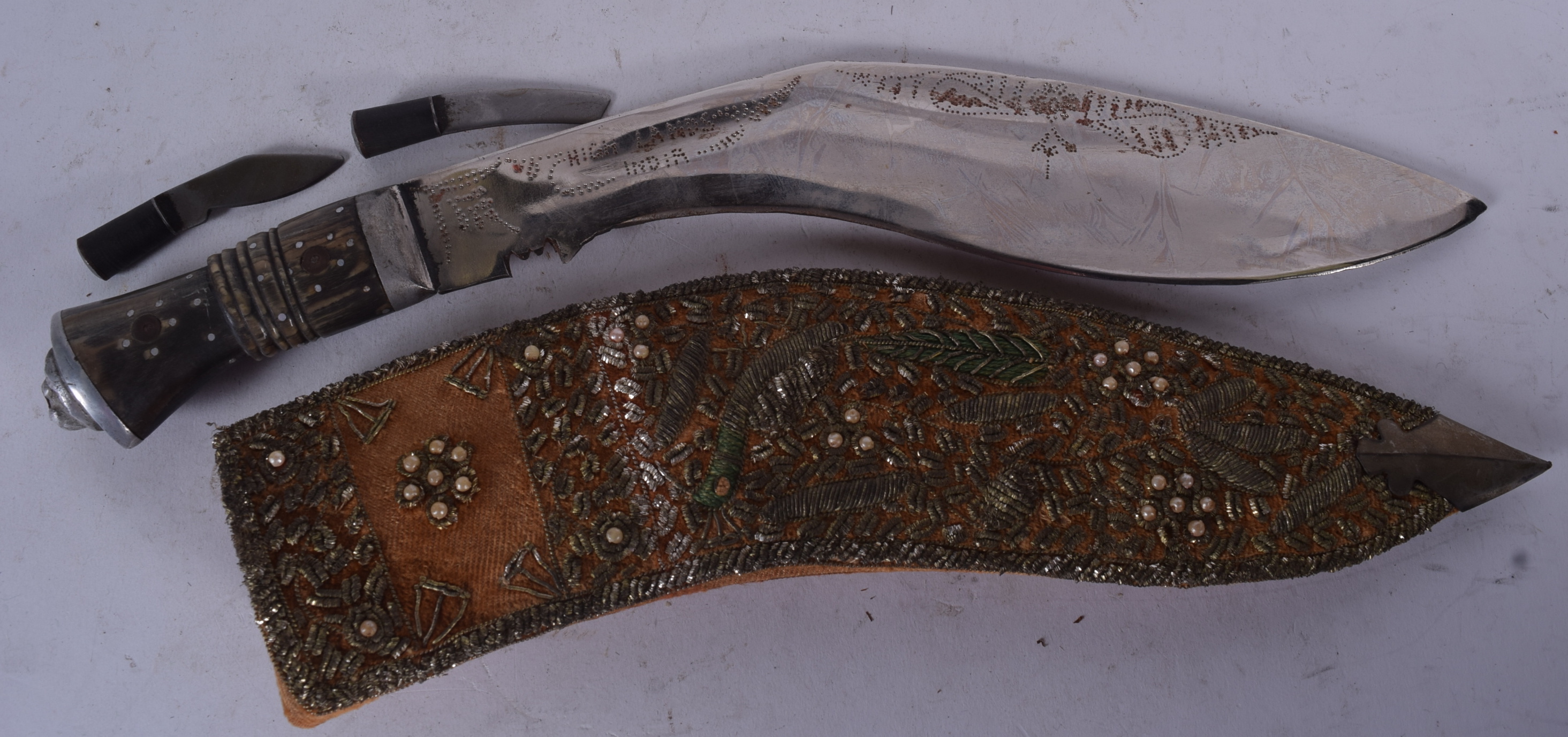 A NEPALESE BUFFALO HORN HANDLED KUKRI, together with an embroidered scabbard. 41 cm long.