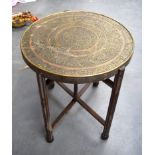 AN EARLY 20TH CENTURY ISLAMIC BRASS TRAY TOP TABLE, decorated with extensive calligraphy. 84 cm x 5