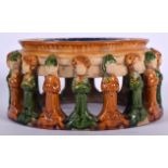 A CHINESE CARVED SANCAI POTTERY STAND, formed held aloft with a ring of females. 21 cm wide.