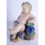 A 19TH CENTURY CONTINENTAL MAJOLICA PUTTI modelled reclining. 24 cm x 21 cm.