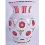 A BOHEMIAN CRANBERRY WHITE OVERLAID GLASS VASE painted with flowers. 20 cm high.