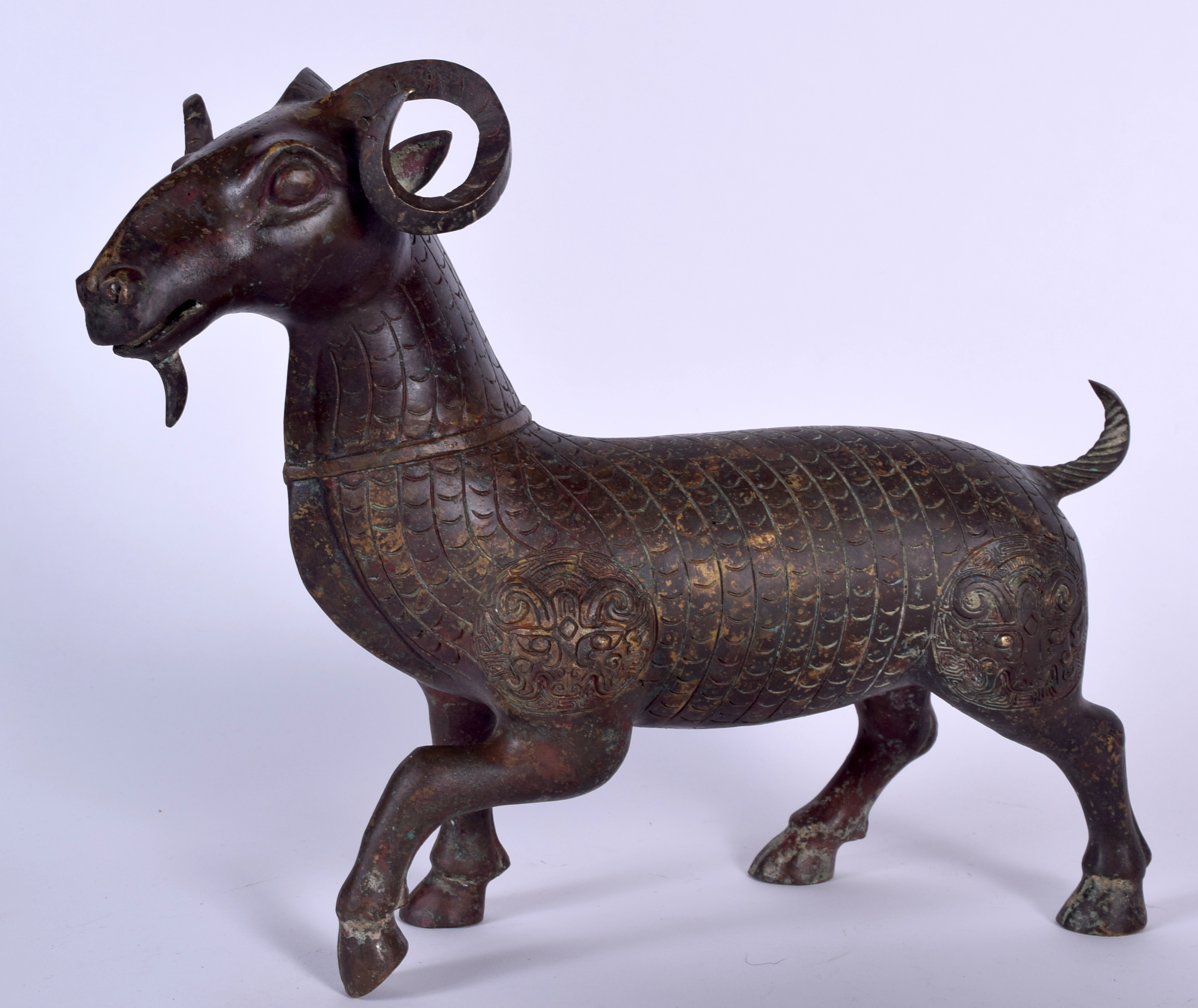 A LARGE CHINESE BRONZE STATUE OF A RAM, decorated with taotie mask heads. 29 cm x 35 cm.