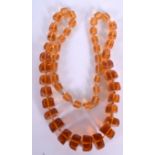 AN EARLY 20TH CENTURY CARVED AMBER NECKLACE, formed with facetted beads. 72 cm long and weight 77 g