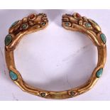 A CHINESE SINO TIBETAN YELLOW METAL BANGLE, inset with turquoise and coral stones. 8.25 cm wide.