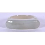 A CHINESE CARVED JADE RING, formed of rounded tablet type design. 3 cm wide.