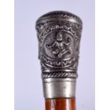 AN EARLY 20TH CENTURY INDIAN SILVER TOP WALKING CANE, decorated in relief with Buddhistic figures e