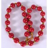 A RED CORAL TYPE BEAD NECKLACE, formed with yellow metal spacers. 38 cm long.