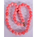 A CHINESE PINK CORAL NECKLACE, carved with symbols. 50 cm long.