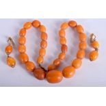 AN ANTIQUE CARVED AMBER NECKLACE with matching earrings. 51 grams. Necklace 40 cm long, largest bead