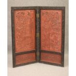 A CHINESE EBONISED WOOD FOLDING TWO SECTION ROOM SCREEN, c.1900, with cinnabar lacquer type panels