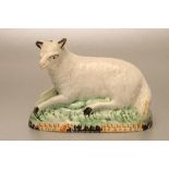 A YORKSHIRE PEARLWARE SHEEP, c.1790, recumbent on a naturalistically moulded base painted in Pratt