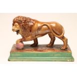A CONTINENTAL MAJOLICA LION, late 19th century, its front left paw resting on a pink ball and