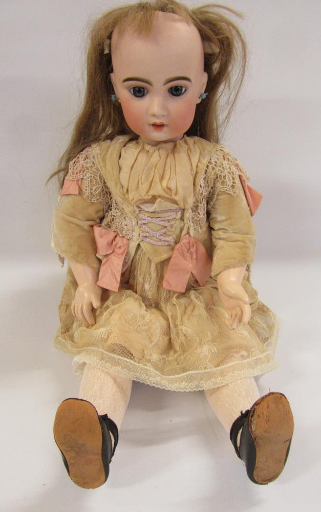 A Jumeau Bebe bisque head doll with fixed blue paperweight glass eyes, open mouth and teeth, pierced