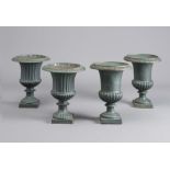 A SET OF FOUR CAST IRON URNS of fluted campana form with ovolu moulded rim, fluted socle and