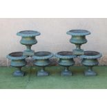A SET OF SIX CAST IRON URNS of half fluted campana form with deeply moulded ovolu rim, turned