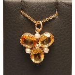 A CITRINE PENDANT, the three oval facet cut stones claw set with three seed pearls between,