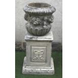 A COMPOSITION STONE URN of waisted half fluted form with ribbon tied floral swags in high relief, (