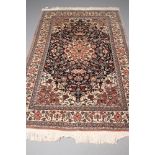 A PERSIAN STYLE RUG, modern, the navy blue field with ivory and pink central gul and spandrels and