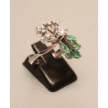 AN EMERALD AND DIAMOND COCKTAIL RING, the central diamond of approximately 0.25cts, claw set to an