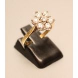 A SEVEN STONE DIAMOND CLUSTER RING, the round brilliants claw set to a plain 18ct gold shank,