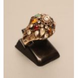 AN INDIAN STYLE BOSS RING, open back collet set with multi-gems to open shoulders and a plain shank,