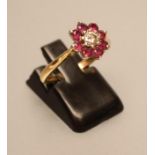 A RUBY AND DIAMOND CLUSTER RING, the brilliant cut diamond claw set to a border of eight small