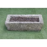 A SANDSTONE TROUGH of shallow oblong form with mildly tapering rusticated sides, 26 1/2" x 12 1/2" x