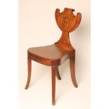 A GEORGIAN MAHOGANY HALL CHAIR, early 19th century, the waisted back with carved shield and with