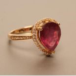 A RUBY AND DIAMOND DRESS RING, the pear cut ruby of approximately 5.80cts claw set to a border of