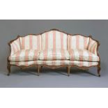 A LOUIS XVI STYLE WALNUT FRAMED SOFA of serpentine outline carved with flowers and scroll work and