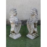 A PAIR OF COMPOSITION STONE HERALDIC LIONS modelled seated and resting their front paws on a shield,