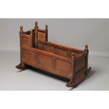 A JOINED OAK CRADLE, early 18th century, the raised back with turned ball finials, fielded panels to