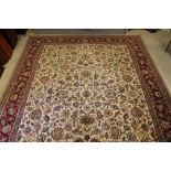 A PERSIAN CARPET, the ivory field with all over bold design of scrolling foliage and flowers