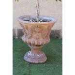 A TERRACOTTA URN of half fluted campana form, moulded in high relief with masks and berried leaf