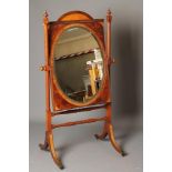 A MAHOGANY CHEVAL MIRROR, the bevelled oval plate within an arched moulded edged oblong surround