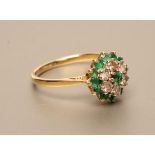 AN EMERALD AND DIAMOND CLUSTER RING, the central emerald claw set to a border of six small