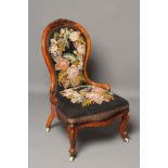 A VICTORIAN WALNUT FRAMED NURSING CHAIR of spoon back form upholstered in gros point with flowers on