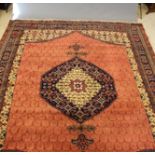 A PERSIAN STYLE CARPET, the madder field with repeating shield pattern in ivory and centred by a