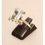 A COCKTAIL RING, the facet cut oblong aquamarine with "wrap-over" angles each set with a diamond