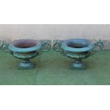 A PAIR OF CAST IRON URNS of shallow campana form with raised foliate scrolled handles, leaf