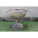 A LARGE TRELLIS MOULDED COMPOSITION STONE URN, the shallow bowl with ovolu rim, turned leaf