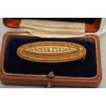 A LATE VICTORIAN OVAL BROOCH, centred by a line of thirteen graduated old cut diamonds within a