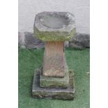 A SANDSTONE BIRD BATH, of square form, the canted bath on tapering stem and stepped base, 12" x 27