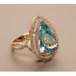 A TOPAZ AND DIAMOND DRESS RING, the pear cut blue topaz of approximately 7.55cts claw set to an open