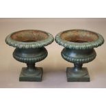 A PAIR OF CAST IRON URNS of half fluted campana form with deeply moulded ovolu rim, turned socle and