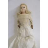 An early 20th century wax shoulder head doll with fixed black/white glass eyes, blonde mohair wig,